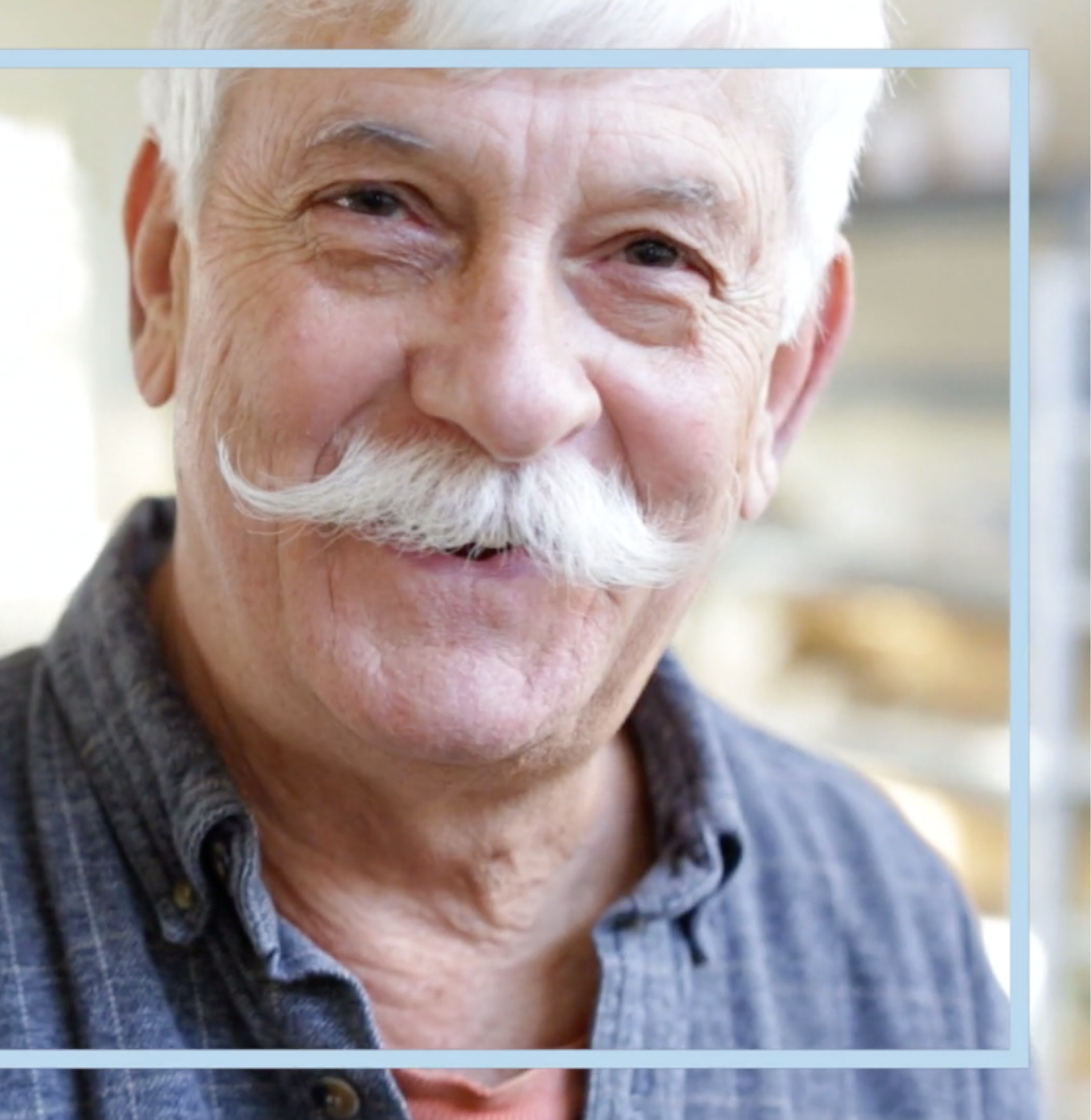 A smiling older man with a light blue border.