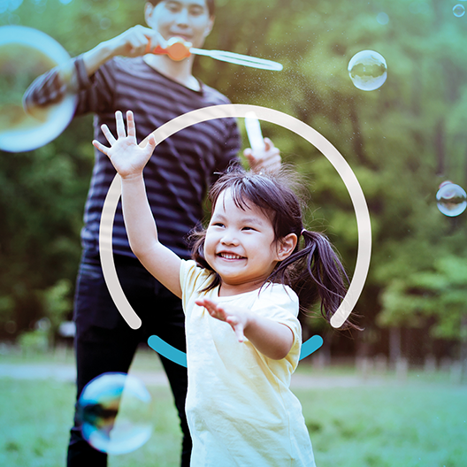 An adult and child play with bubbles outside