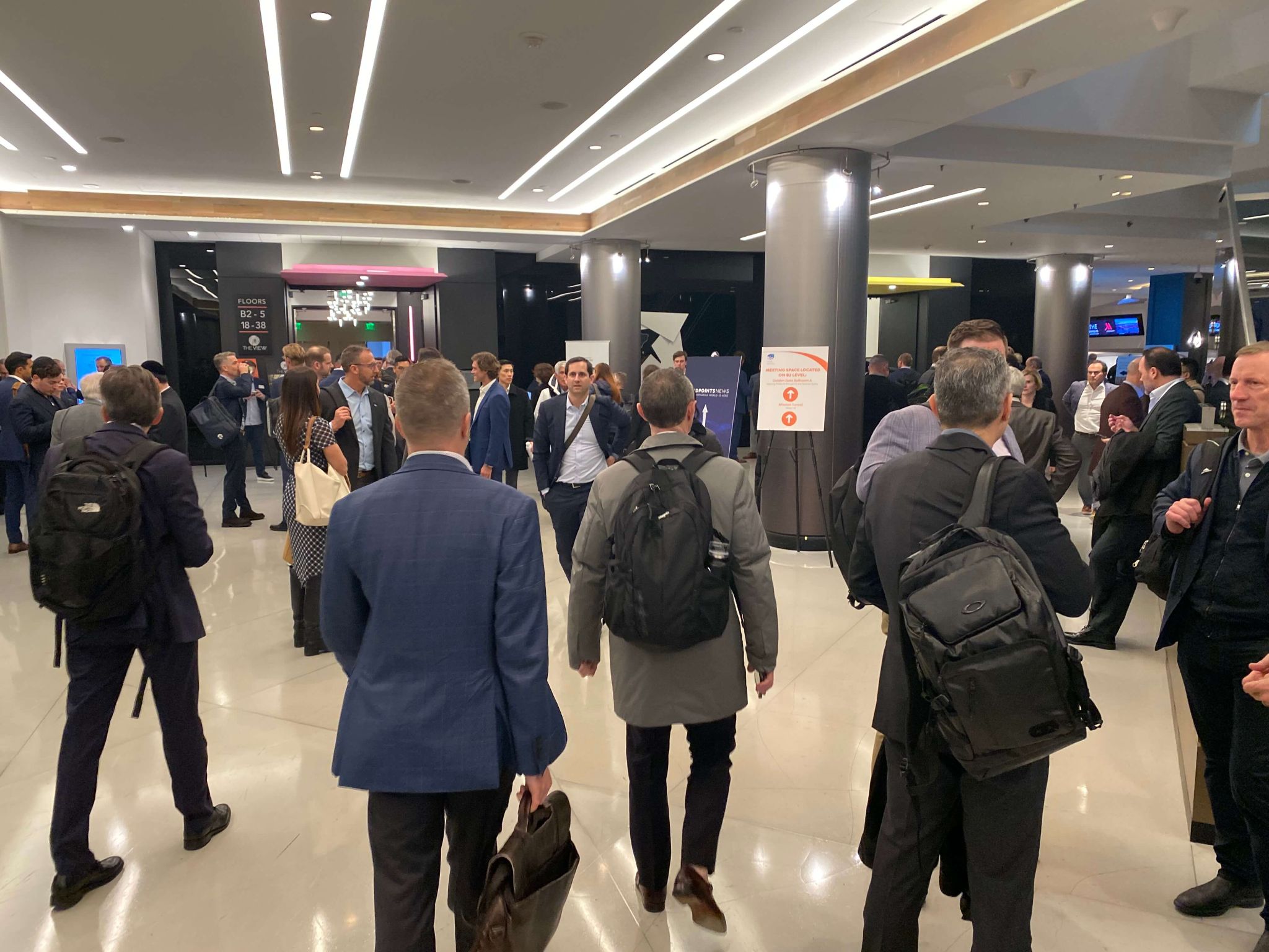 A crowd of people walk through a convention hall