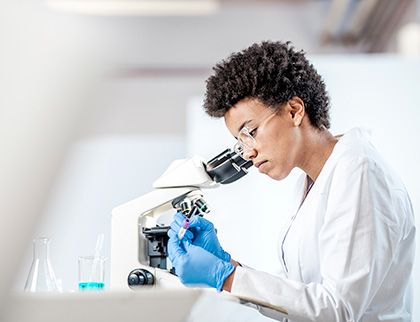 A scientist inspects a sample under a microscope.