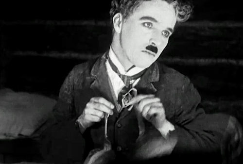 A GIF of Charlie Chaplin playing with two forks.