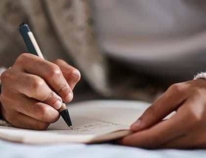 A closeup photo of a person writing with a pen on a piece of paper.