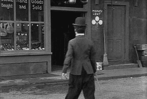 A GIF of Charlie Chaplin walking in a comical manner.