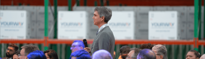 Man smiling and talking to a crowd